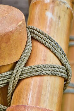 Dikey ve yatay parlak bambu direklerin birbirlerine kalın bir iple bağlanmış görüntüsü