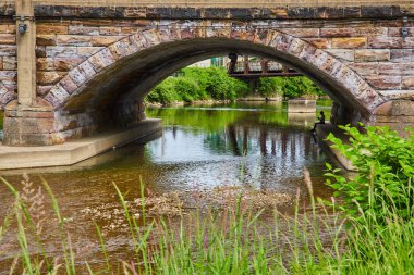 Nehir 'in, muhteşem taş köprü kemerinin altında kitap okuyan biriyle birlikte aktığını hayal et.
