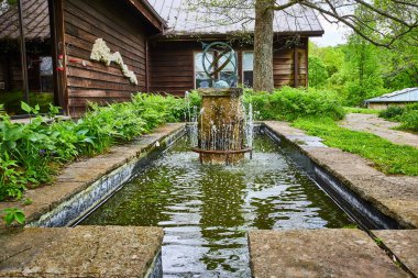 Kabin yakınında ok ve kanal bulunan soyut dönen küreyle süslü su çeşmesinin görüntüsü