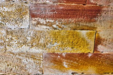 Geniş yatay tuğla görüntüsü, etrafını çevreleyen taştan tuğlalar, parlak toprak tonları ve beyaz sermaye