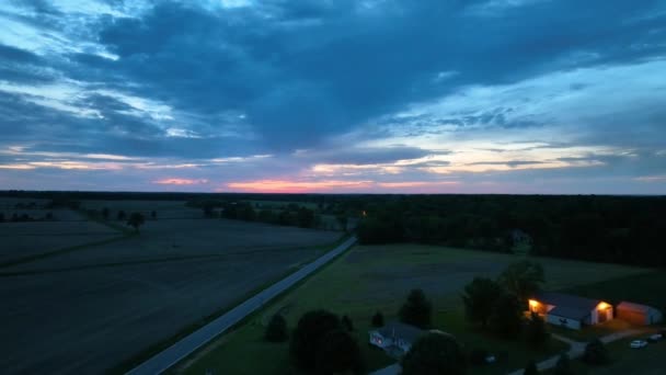 深い青と輝かしいピンクの日没で田舎の農家に向かって上空のビデオのビデオ — ストック動画