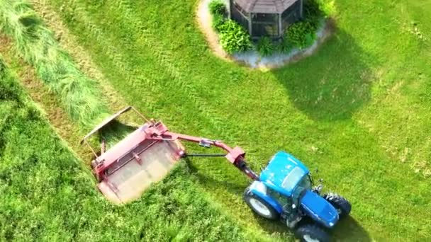 背の高い草を刈るトラクターの下向きの空中ビデオのビデオ — ストック動画