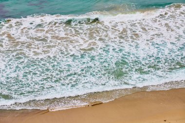 Temiz kumsala çarpan deniz mavisi dalgasının Aerial zen görüntüsü