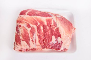 Beyaz arka planda beyaz tepside taze kesilmiş çiğ domuz kaburga eti görüntüsü