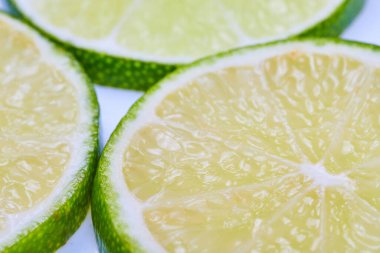 Beyaz etli ve beyaz arkaplanlı üç yeşil limon diliminin Parlak görüntüsü