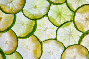 Turunçgillerin arka planında üst üste binen yeşil limon dilimlerinin resmi