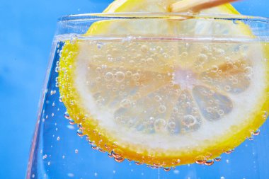 Mavi arkaplanlı köpüklü bardaktaki limon diliminin yakın plan görüntüsü