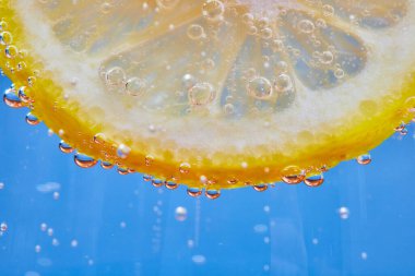 Mavi arkaplanda baloncuklu limon diliminin kenarlı makro görüntüsü