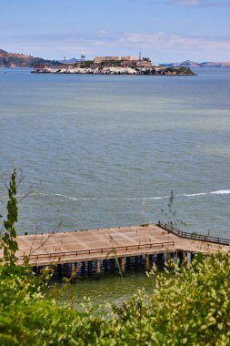 Uzakta Alcatraz adası olan yeşil çimenli ve rıhtımın görüntüsü