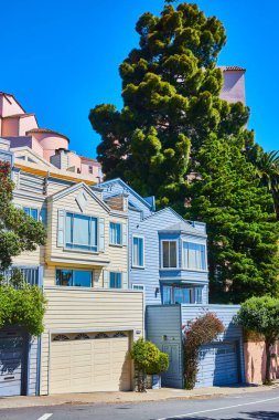 Sarı ve mavi evlerin yan yana koydaki pencerelerin altındaki garajın resmi