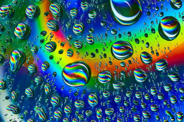 Image of Swirls of rainbow colors inside wobbly bubbles on dark silvery blue rainbow burst background asset