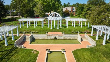 Lakeside Park 'taki açık hava düğün yerindeki beyaz sarmaşıkların önündeki su birikintilerinin görüntüsü