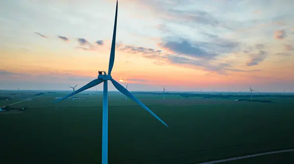 Image of Gorgeous pink and gold sunset aerial on wind farm close up of turbine in field