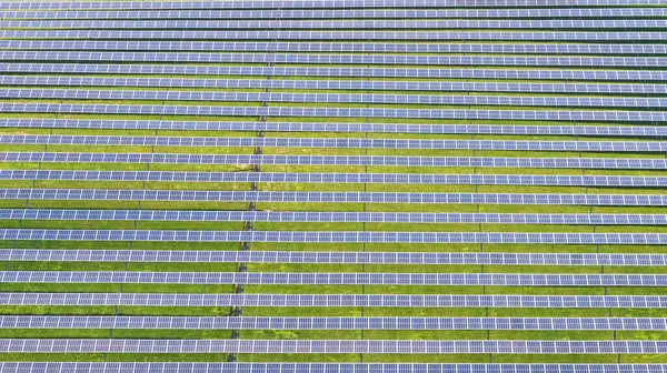 Image of Background asset aerial wide view of row after row of solar panels in grassy field