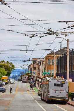 Tepedeki caddede ikinci otobüsle yenilenebilir enerji kabloları olan Temiz Hava Aracı görüntüsü