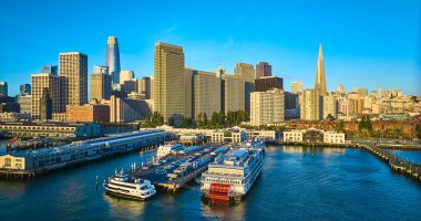 Hava gündoğumu görüntüsü rıhtımdaki gemilerin üzerinde San Francisco gökdelen silueti olan.