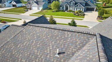 Image of Aerial over earthtone roof in neighborhood on summer day clipart