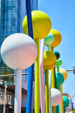 Soyut heykellerin üzerinde mavi ve yeşil tonlarda sarı ve beyaz renkli toplar tasviri