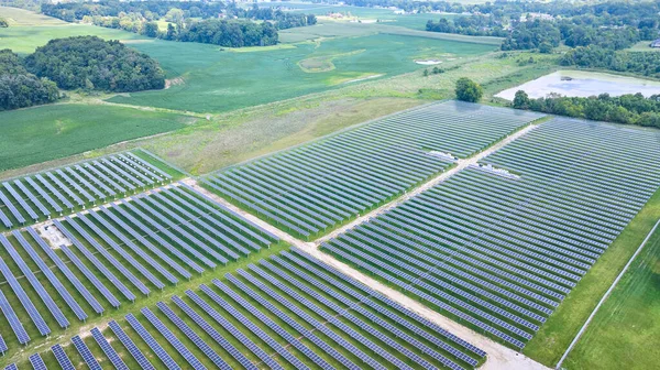 Image of Solar panels facing straight up in aerial over solar farm with swamp and farmland around it