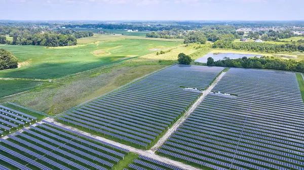 Image of Aerial Midwest solar farm with solar panels in rural area near farmland and swamp