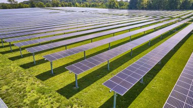 Çiftlik havasındaki güneş panelleri sıralarının etrafındaki yeşil çimenlerin görüntüsü