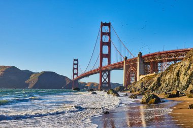 Arkaplanda Golden Gate Köprüsü olan kumlu sahile çarpan dalgaların görüntüsü
