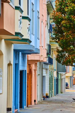 Üzerinde pastel renkli binaların girişleri olan asılmış bir ağaç resmi
