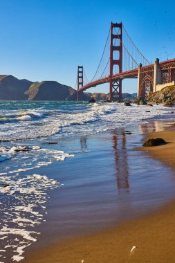 Deniz köpüğü ve dalgaların kayalık kıyılara ve Golden Gate Köprüsüne çarptığı Islak Kumsal görüntüsü