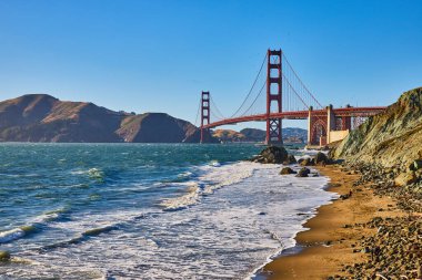 Golden Gate Köprüsü 'nün görüntüsü kumlu sahilden kayalara çarpan dalgalarla