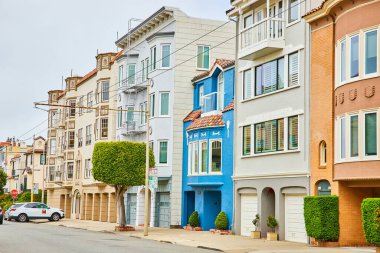 Yakın sıkışık ev satırları arasındaki pencerelerin üzerinde MMM olan Çömelme Mavi Ev resmi