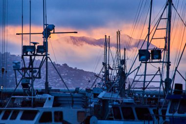 Sis ve bulutlarla örtülü dağların üzerinde altın gün batımına sahip üç geminin görüntüsü