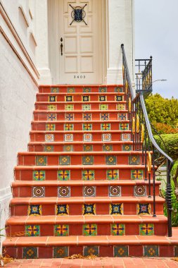 Her merdivende beyaz kapıya giden kırmızı tuğlalı basamakların resmi