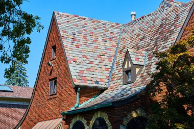 Mavi gökyüzünün altındaki kırmızı tuğlalı evdeki çok renkli fayansların resmi