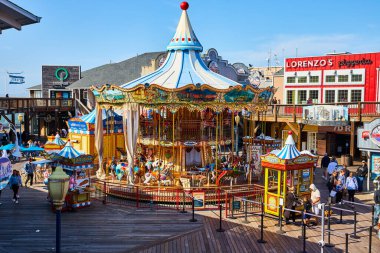 39. rıhtımdaki hayvan atlıkarıncasında insanların restoranlarla çevrili olarak kuyruğa girmesi.