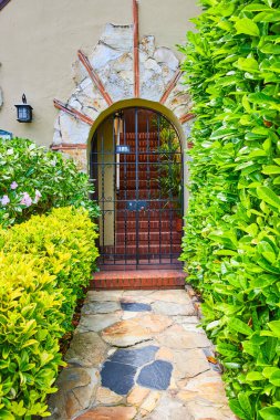 San Fransisco 'nun yeşil çalılıklarda sıralanmış evinin kapılı taş kemer girişine giden kaldırım resmi