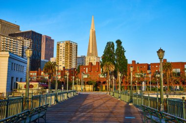 San Francisco 'daki gökdelenleri aydınlatan altın ışıkla dolu iskeleden gün doğumunun görüntüsü