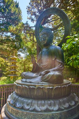 Güneş ışığının ışığı, Buda heykeline hafifçe vururken, arka planda palmiyeler yükselmiş ve altın renginde pagoda görünümü