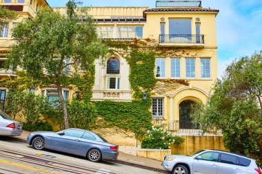 Sokakta arabalı dik tepenin ve pencereli büyük dairenin görüntüsü