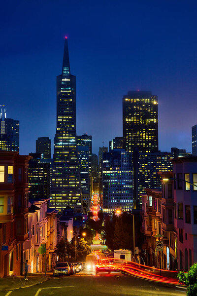 Image of Motion blur of cars on long hill leading to downtown Transamerica Pyramid on foggy night
