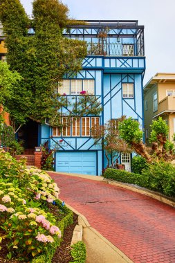 Lombard Caddesi 'nde muhteşem balkonu ve kırmızı tuğlalı yolu olan mavi evin görüntüsü.