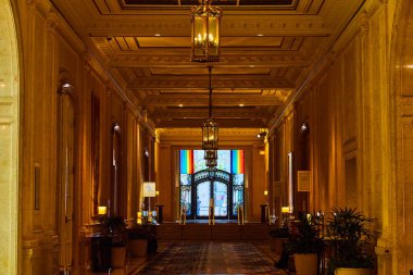 Altın yansıtıcı koridorun sonundaki gökkuşağı bayraklarıyla çerçevelenmiş süslü kapı aralığı