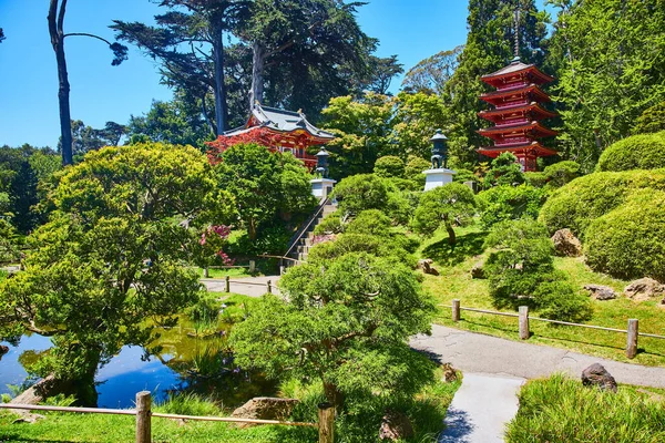 Mavi göletli Muhteşem Japon Çay Bahçesi 'nin resmi ve tepede fenerli iki kırmızı pagoda binası.
