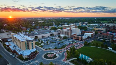 Muncie 'nin görüntüsü, şehir merkezindeki binaların ve otelin havasıyla ufukta batmakta olan In güneşi heykel ve parkın yanında.