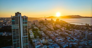 San Francisco 'nun gölgeli görüntüsü. Güneş dağların ardında batıyor. Koyda gökyüzünde binaların üzerinde.