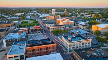 Muncie Indiana şehir merkezinin şafak vakti binalar ve su kulesi üzerinde sarı gündoğumu ışıklarıyla görüntüsü.