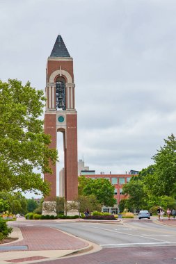 Shafer Tower Ball State Üniversitesi kampüsünde yeşil ağaçların altında yürüyen öğrencilerin görüntüsü