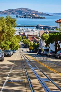 Güneşli bir günde Pier, San Francisco, CA ile Alcatraz Adası 'na giden tramvaylar için raylı boş caddenin görüntüsü