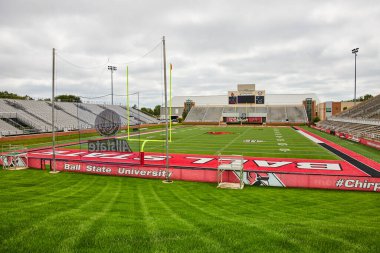 Scheumann Stadyumu görüntüsü yemyeşil çimenler, boş stadyum koltukları ve futbol sahasında sarı kale direği.