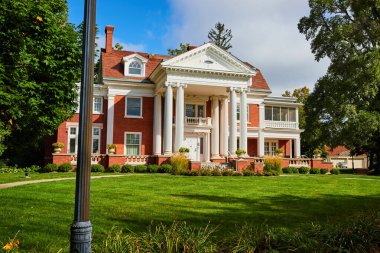 Minnetrista Müzesi 'ndeki Maplewood malikanesinin resmi ve yeşil çimenli ve mavi gökyüzü olan bahçeler.