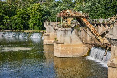 Maumee Nehri Barajı 'nın, şelalelerin üstündeki beton sütunlarda paslı ekipmanlarla ve Fort Wayne' deki orman geçmişiyle görüntüsü.